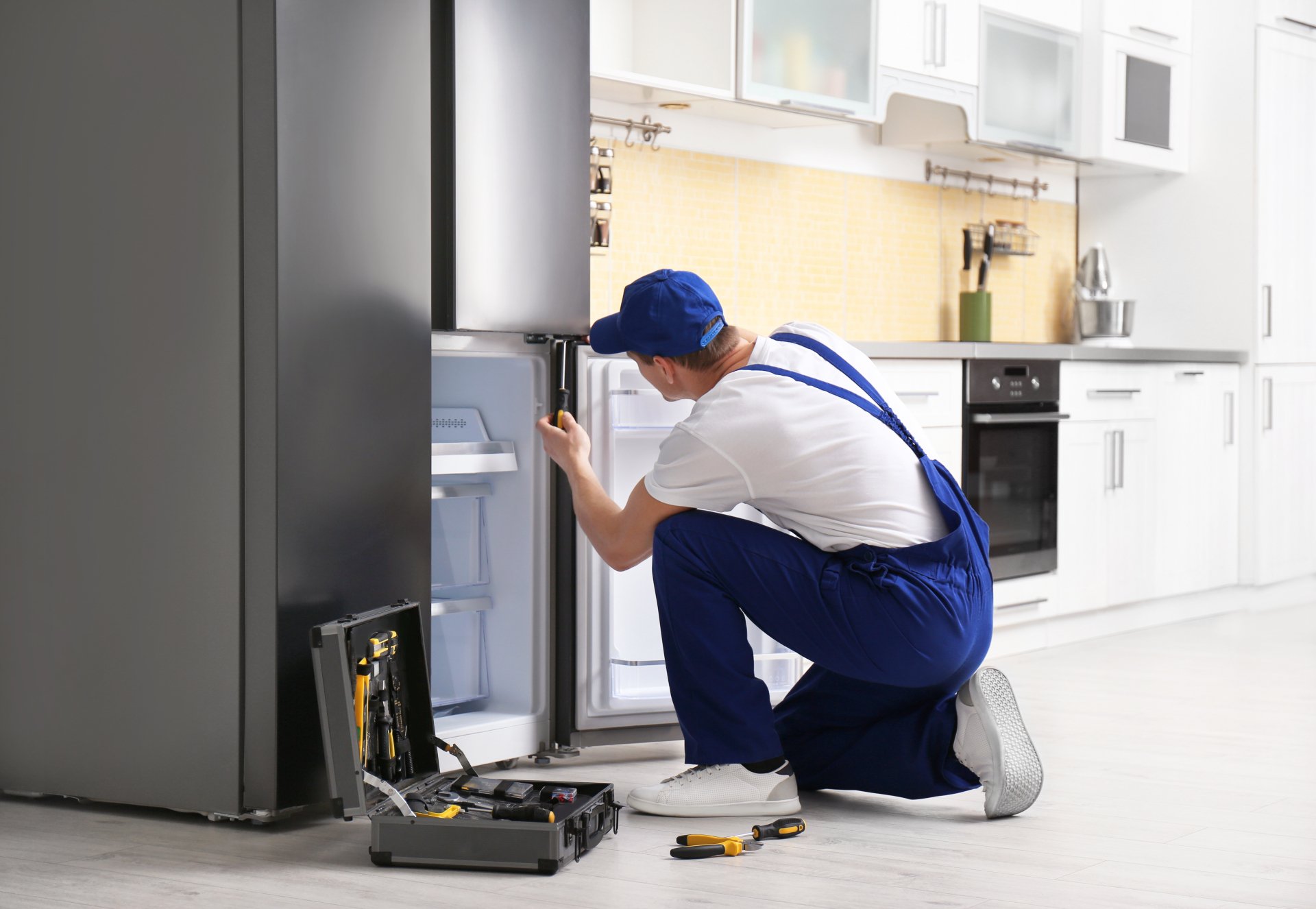 a technician repairing a refrigerator - Brooklyn Appliance Repair Pros