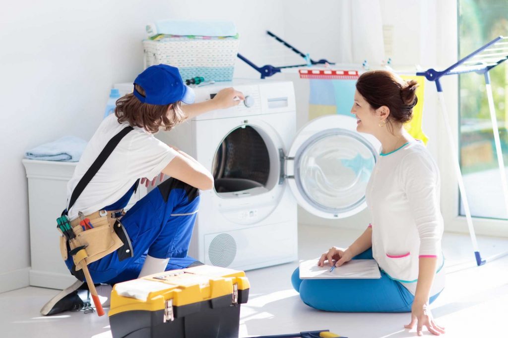 a technician repairing a washer while woman is watching - appliance repair service Brooklyn